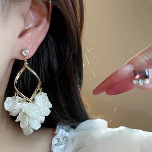 Detail shot of elegant French style zircon earrings with white petal tassel dangles.