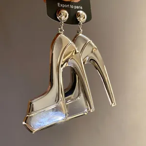 Detailed macro view of silver metallic high-heeled shoe pendant earrings with glossy finish