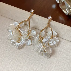 Detailed view of elegant gold-toned earrings with zircon studs and pearly white flower petals.