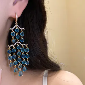 Detaillierte Makroansicht von eleganten blauen Zirkonia-Kronleuchter-Ohrringen am Ohr
