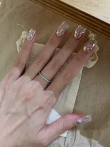 Detailansicht eines minimalistischen mintgrünen Steinrings an einer Hand mit Sternnägeln.