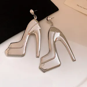 Macro view of metallic high-heeled shoe pendant earrings with shiny silver finish.