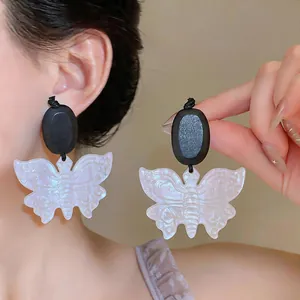 Détail de boucles d'oreilles papillon en résine vintage avec élégants accents de bois noir