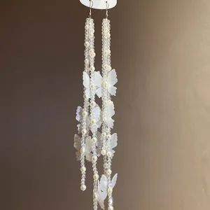 Close-up detail of elegant white chiffon butterfly and pearl beaded long tassel drop earrings