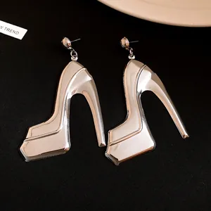 Close-up of silver metallic high-heel shoe pendant earrings on black background
