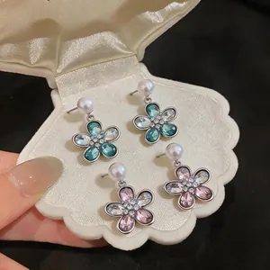 Close-up of elegant flower drop earrings with pearls and crystals in a shell box.