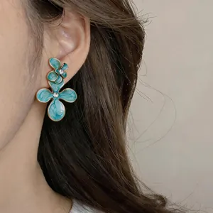 Vue détaillée des boucles d'oreilles fleurs en émail sarcelle et strass