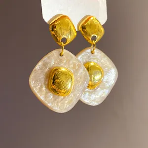 Dettaglio orecchini pendenti vintage a rombo in resina perlata e oro molto eleganti