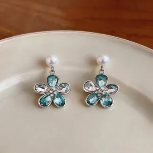 Macro view of floral dangle earrings with teal crystals and white pearl studs