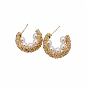 Elegant gold C-shaped earrings featuring dainty pearls and sparkling zirconia stones.