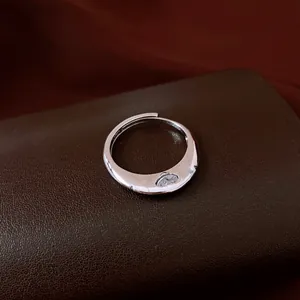Silver-toned wavy ring detail with zircon stone inlay on brown leather background
