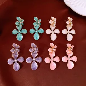 Vue détaillée de boucles d'oreilles fleurs en émail en vert, blanc, violet et rose