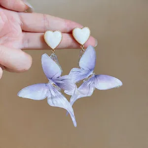 Vue détaillée de grandes boucles d'oreilles papillon en résine violette avec cœur