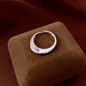 Close-up detail shot of vintage zircon open ring with wavy silver design on brown box.