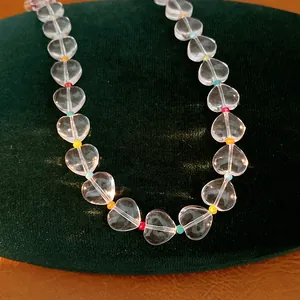Close-up of clear heart crystal beads with colorful accents on a green velvet stand