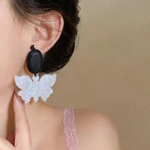 Boucles d'oreilles papillon ethniques vintage en bois et résine sur une oreille