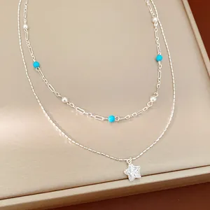 Macro view of a double layer silver necklace featuring a sparkling star pendant and blue beads.