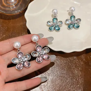 Macro view of elegant crystal flower drop earrings with pearl tops and silver finish.