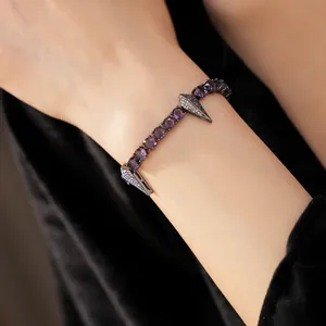 Detailed view of punk style bracelet with purple zircons and diamond pendants on wrist