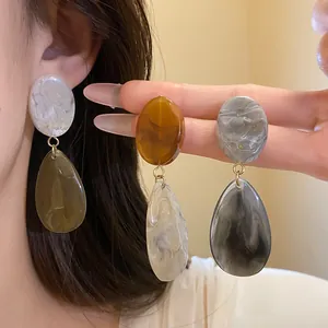Vue détaillée de diverses boucles d'oreilles pendantes en résine aux motifs marbrés