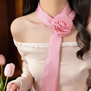 Close-up detail of a pink chiffon flower scarf necklace accessory worn by a model