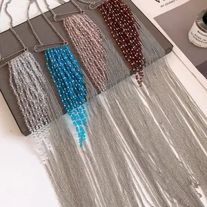 Détail de colliers à pompons de perles bleues, roses et rouges avec chaînes argentées.