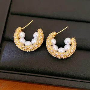 Close-up detail of vintage style gold C-shaped hoop earrings with pearls and zircons
