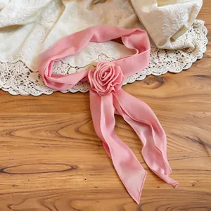 Elegant pink chiffon rose necktie scarf accessory on lace and wooden background