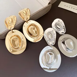 Dettaglio degli orecchini pendenti a cappello da cowboy in metallo oro e argento