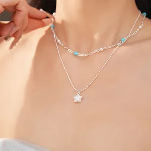 Close-up of double-layer necklace with zircon star pendant and turquoise beads