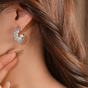 Detail view of elegant silver C-shaped zircon earrings with pearls on a female model