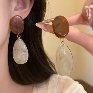 Vue détaillée de boucles d'oreilles en résine avec ovales bruns et gouttes marbrées