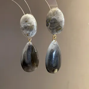 Vue rapprochée de boucles d'oreilles élégantes en résine marbrée avec anneaux dorés