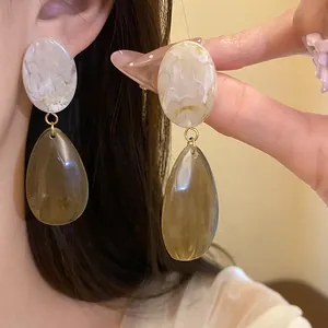 Gros plan détaillé de boucles d'oreilles en résine avec pendentifs ovales marbrés.