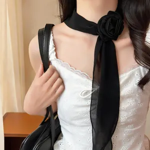 Close-up detail of a elegant black chiffon flower scarf necklace worn by a model