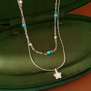 Close-up of elegant double-layer necklace featuring star pendant and beads in velvet box