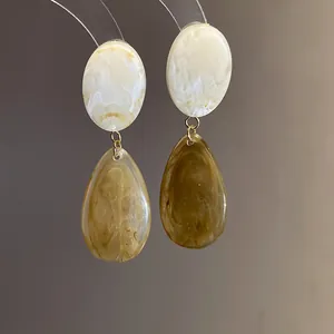 Gros plan de boucles d'oreilles en résine avec motif marbré et goutte d'eau
