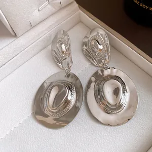Dettaglio di orecchini pendenti vintage in metallo argento a forma di cappello da cowboy