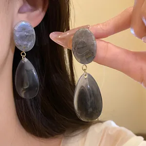 Gros plan détaillé des élégantes boucles d'oreilles en résine marbrée grise en goutte