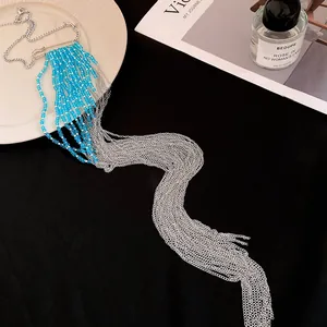 Vue détaillée du collier à pampilles en chaîne argentée avec perles bleues sur fond noir