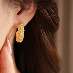Detailed macro view of elegant gold C-shaped earrings with sparkling zircons and pearls
