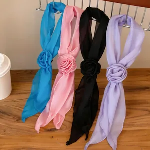 Close-up detail of four elegant chiffon flower scarf necklaces in assorted colors on rack