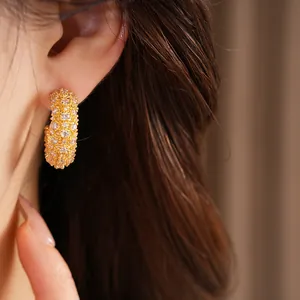 Exquisite close-up view of gold C-shaped stud earrings fully paved with sparkling cubic zirconia