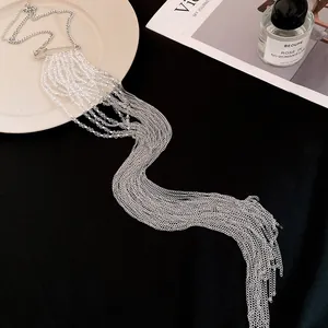 Vue détaillée d'un long collier à pompons argentés avec fermoir épingle à nourrice chic.