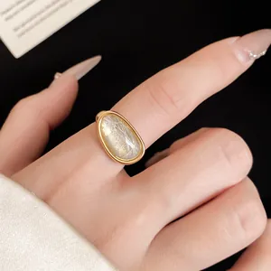 Macro view of an 18k gold plated ring featuring a natural stone inlay on a finger.