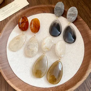 Gros plan de boucles d'oreilles en résine marbrée sur un plateau en bois