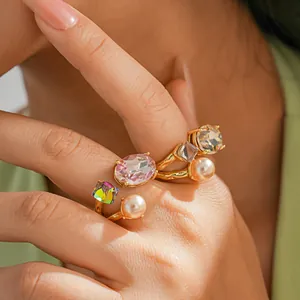 Detailed close-up of gold-plated open rings with faux pearls and sparkling crystals