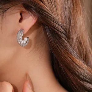 Close-up detail of luxury silver C-shaped stud earrings with pearls and zirconia studs