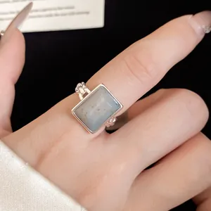 Elegant 18k gold plated open ring with a rectangular light gray stone on a finger.