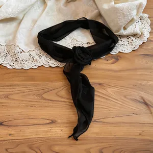 Detailed view of elegant black chiffon flower scarf choker on a wooden background